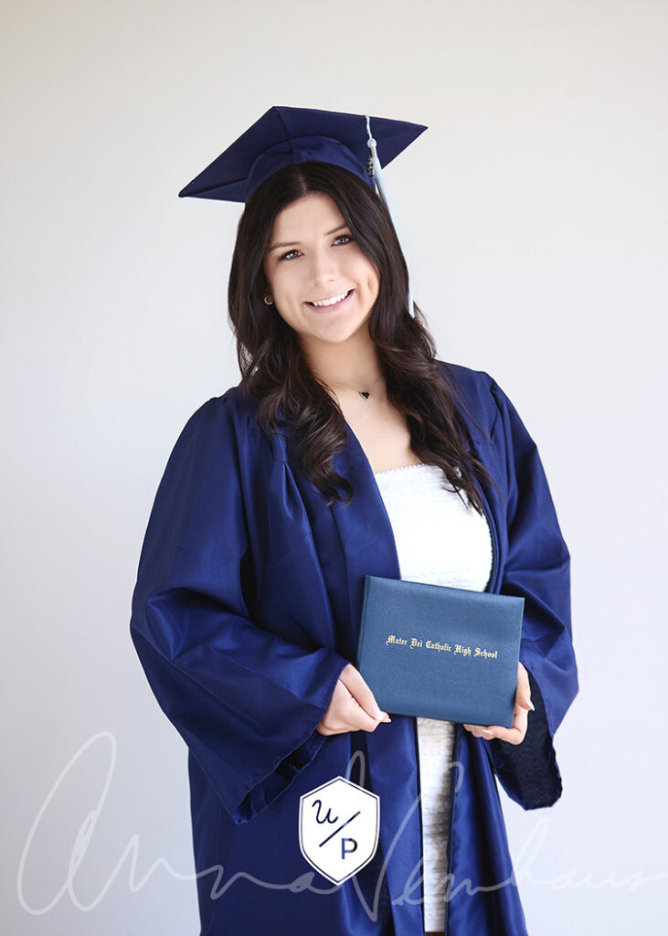 senior girl in a navy cap and gown holding her diploma